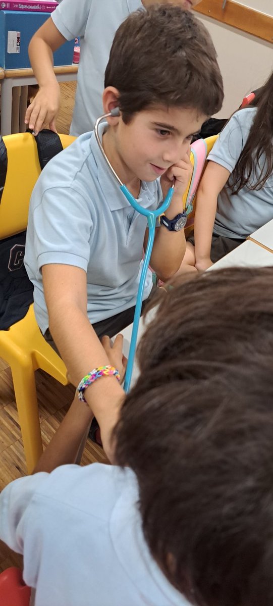 Um aluno a ouvir os batimentos do coração de um colega, com um estetoscópio